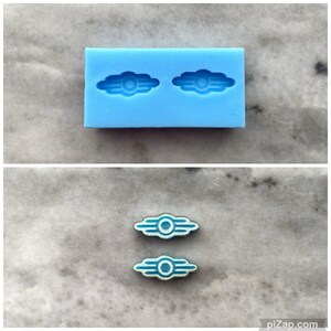 May include: Two blue and white Vault-Tec logo epoxy resin pieces on a light gray surface. The pieces are made from a silicone mold shown in the top image.