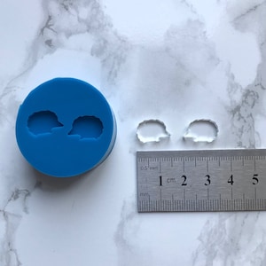 Könnte beinhalten: Zwei transparente Kunststoffformen von Igeln, jede etwa 1 cm im Durchmesser, neben einer blauen Silikonform mit zwei Igelformen. Ein Lineal ist zur Skalierung enthalten.
