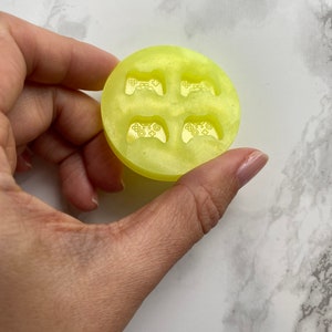 May include: A yellow silicone mould with four impressions of a video game controller. The mould is designed for making resin crafts.