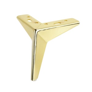 Könnte beinhalten: Goldenes Möbelbein aus Metall mit dreieckiger Form und einer spitzen Spitze. Das Bein hat eine glatte, polierte Oberfläche und ist für die Unterstützung von Möbeln konzipiert.