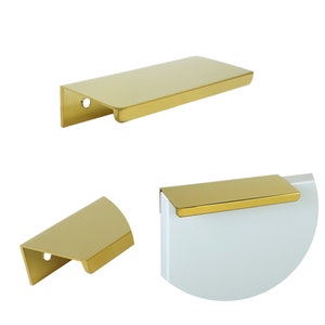 Op de afbeelding: Drie gouden kastgrepen met een rechthoekige vorm. De grepen hebben een gladde, gepolijste afwerking.