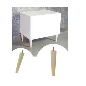 Op de afbeelding: Een witte kast met vier houten poten. De poten zijn taps toelopend en hebben een natuurlijke houtkleur. De kast staat op een grijze vloer.