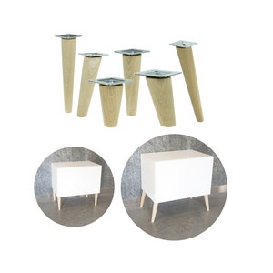 May include: White cabinet with four wooden legs. The cabinet is on a gray background. There are six wooden legs with metal plates on a white background.