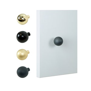 Può includere: Quattro pomelli per armadi in diverse finiture: oro, nero, ottone e grigio scuro. I pomelli sono rotondi e hanno un design semplice.