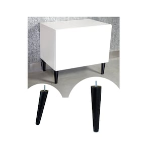 Op de afbeelding: Een witte kast met vier zwarte taps toelopende poten. De poten zijn van hout en hebben een schroefontwerp.