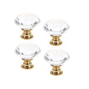 Könnte beinhalten: Satz mit vier klaren Kristall-Knöpfen in Diamantform mit goldenen Sockeln.