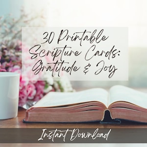 Może przedstawiać: Otwarta książka ze starymi stronami leży na drewnianej powierzchni, obok białego kubka i różowych kwiatów. Nakładka tekstowa brzmi "30 Drukowanych Kart Biblijnych: Wdzięczność i Radość" oraz "Natychmiastowe pobieranie".