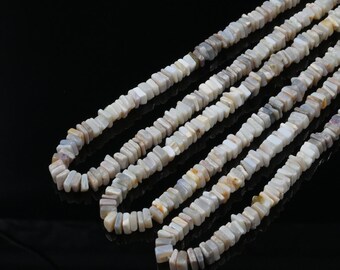 Può includere: Una collana di perline di pietre preziose bianche e grigie, ogni perlina è rettangolare e ha una forma leggermente irregolare. Le perline sono infilate per formare una lunga collana.