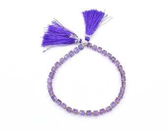 Peut inclure: Un bracelet en améthyste violette avec des perles carrées et des accents de pompons violets.