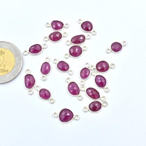 May include: A scattering of 18 silver-toned gemstone connector charms with a faceted ruby-colored stone. Each charm has two jump rings for attaching to jewelry.