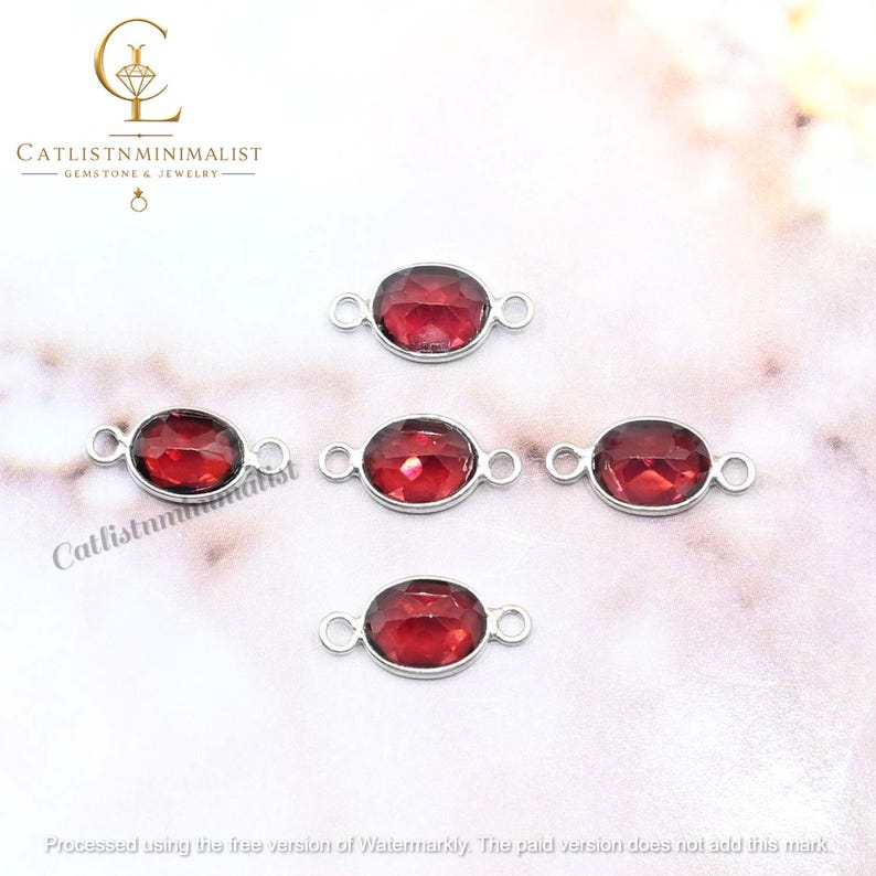 Pode incluir: Quatro conectores de joias de formato oval com pedras preciosas vermelho-escuras facetadas em molduras de metal prateado. Cada conector possui dois pequenos aros circulares nos lados opostos. O logotipo CATLISTNMINIMALIST &eacute; vis&iacute;vel.