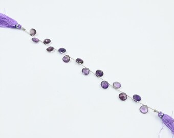 May include: A strand of amethyst gemstone beads, faceted and strung on a silver wire. The beads are a light purple color and have a natural, irregular shape. The strand is finished with a tassel on each end.