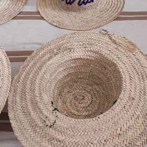 May include: A straw hat with a purple embroidered name "Sarah" on the front. The hat is woven with a herringbone pattern.
