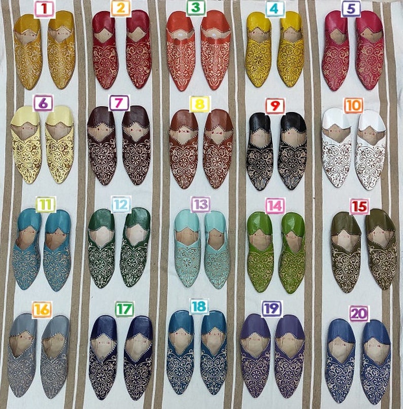 K&ouml;nnte beinhalten: Zwanzig Paar Lederschlappen mit aufwendigen Stickereien in verschiedenen Farben, darunter Gelb, Rot, Braun, Schwarz, Wei&szlig;, Blau, Gr&uuml;n und Lila. Die Schlappen sind in Reihen zu zweit angeordnet und von 1 bis 20 nummeriert.