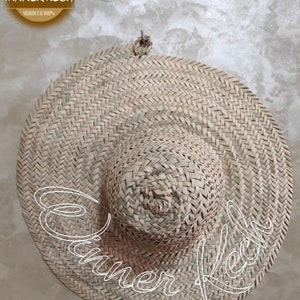 May include: A large, round, woven straw hat with a wide brim. The hat is made of natural straw and has a simple, classic design.