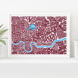 Puede incluir: Un grabado enmarcado que presenta un mapa estilizado de Londres, Inglaterra. El mapa está compuesto por nombres de lugares en color burdeos, con un río azul claro que lo atraviesa. El texto "LEWIS STADIUM" es visible.