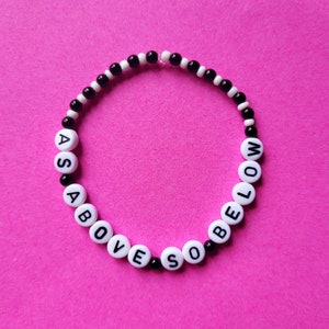 May include: A black and white beaded bracelet with the words "As Above So Below" spelled out on it.