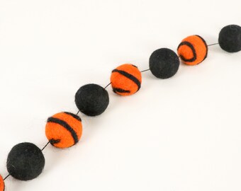May include: A Halloween garland with alternating black and orange felt balls. The orange balls have black stripes.