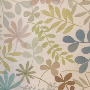 Może przedstawiać: Biała tkanina z powtarzającym się wzorem stylizowanych liści w odcieniach zieleni, błękitu i brązu. Liście są wyszyte na tkaninie.