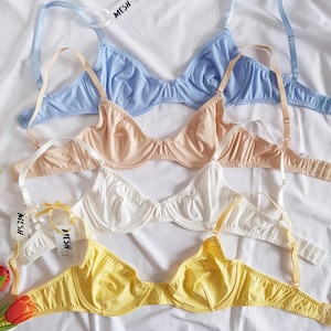 Pode incluir: Quatro suti&atilde;s em diferentes cores: azul claro, bege, branco e amarelo. Os suti&atilde;s s&atilde;o feitos de um material macio e el&aacute;stico e t&ecirc;m uma delicada renda. Os suti&atilde;s est&atilde;o empilhados, com o suti&atilde; azul claro no topo e o suti&atilde; amarelo na parte inferior. Todos os suti&atilde;s s&atilde;o etiquetados com a palavra "MESH".