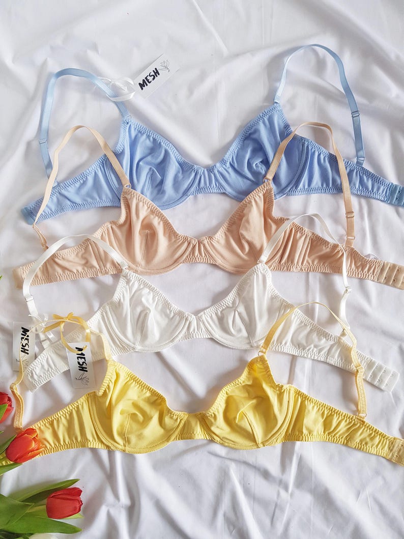 Pode incluir: Quatro suti&atilde;s em diferentes cores: azul claro, bege, branco e amarelo. Os suti&atilde;s s&atilde;o feitos de um material macio e el&aacute;stico e t&ecirc;m uma delicada renda. Os suti&atilde;s est&atilde;o empilhados, com o suti&atilde; azul claro no topo e o suti&atilde; amarelo na parte inferior. Todos os suti&atilde;s s&atilde;o etiquetados com a palavra "MESH".