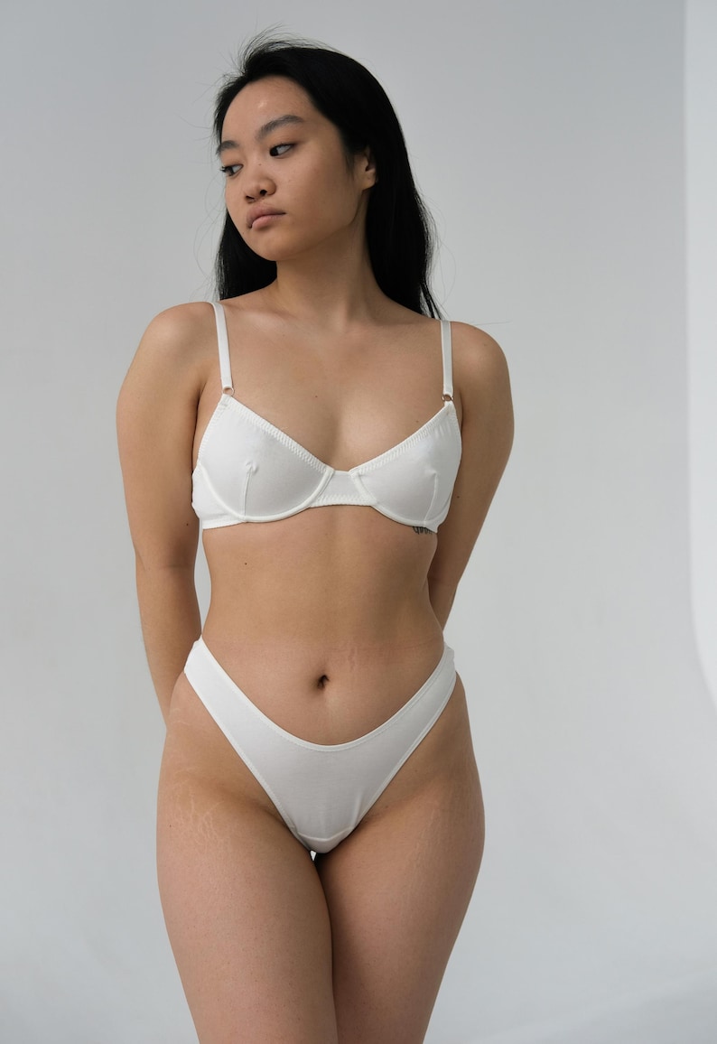 Pode incluir: Conjunto de roupa interior branca, um suti&atilde; e uma calcinha, com um design simples.