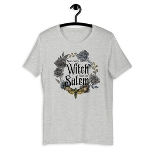 May include: Gray t-shirt with a black and white floral design and a moth. The text "Not every Witch lives in Salem" is printed on the shirt.