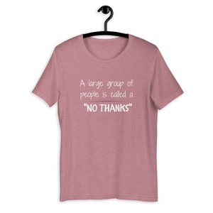 Puede incluir: Una camiseta de color rosa claro jaspeada con un gr&aacute;fico blanco que dice "A large group of people is called a "NO THANKS""