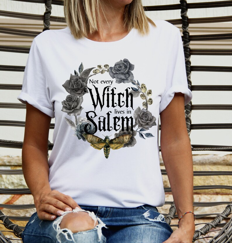 May include: White t-shirt with a black and gray floral design and the text "Not every Witch lives in Salem".