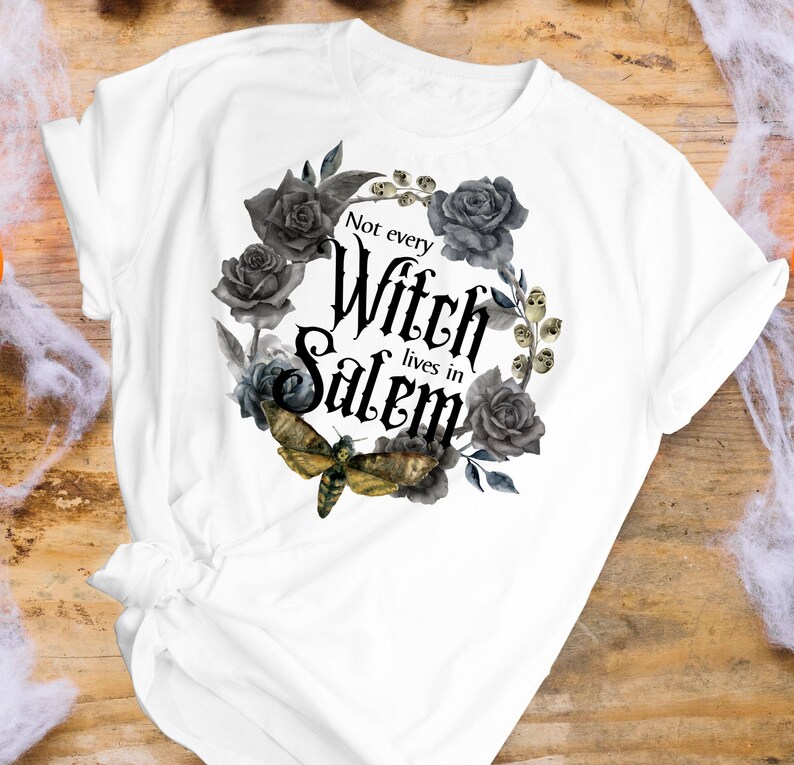 May include: White t-shirt with a black and gray floral design and the text "Not every Witch lives in Salem".