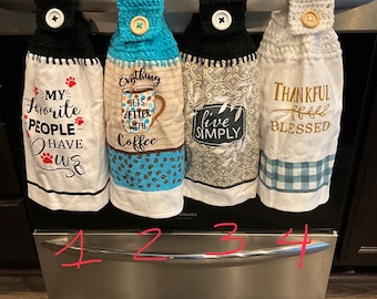 May include: Four hanging kitchen towels with crocheted tops and buttons. The first says MY FAVORITE PEOPLE HAVE PAWS. The second says Everything GETS BETTER WITH Coffee. The third says live SIMPLY. The fourth says THANKFUL BLESSED with a plaid pattern.