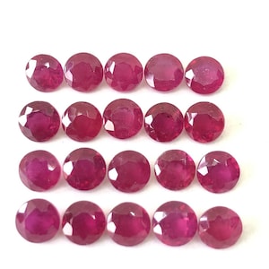 Peut inclure: Une collection de 18 pierres précieuses de rubis rondes et facettées. Les rubis sont de couleur rouge foncé et sont disposés en trois rangées de six.
