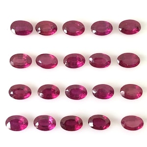 May include: Twenty oval-shaped ruby gemstones arranged in four rows of five. The gemstones are a deep red color and have a glossy finish.