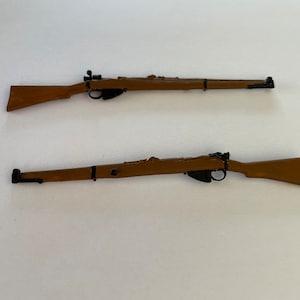 May include: Two miniature brown rifles with black details are displayed against a white background. The rifles have a classic design, with a wooden stock and a long barrel. The rifles are positioned parallel to each other.