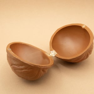 May include: A brown ceramic trinket box shaped like a walnut, with a hinged lid open to reveal the empty interior.