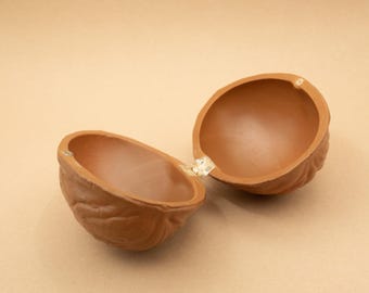 May include: A brown ceramic walnut-shaped trinket box with a hinged lid, open to reveal the empty interior.