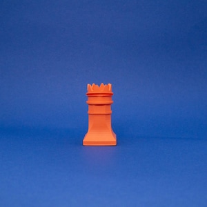 May include: A small, orange plastic castle tower with a crenellated top. The tower is made of several stacked rings.