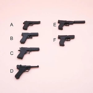 May include: A collection of six miniature black toy pistols arranged in two columns and labeled with the letters A through F. Each small plastic firearm features distinct barrel lengths, grip designs, and trigger guard shapes, presented on a plain background.