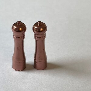 May include: Two rose gold salt and pepper shakers with a classic design.