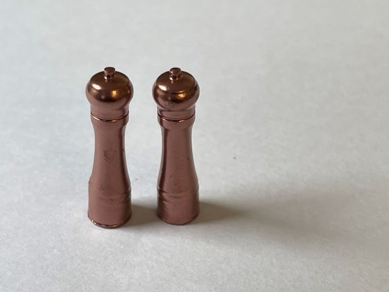 May include: Two rose gold salt and pepper shakers with a classic design.