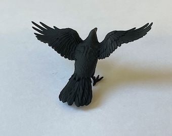 May include: A black crow figurine with its wings spread out. The crow is made of a smooth, matte black plastic.
