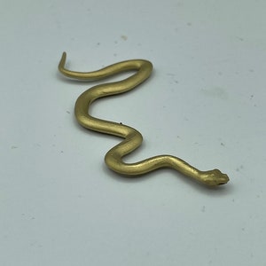May include: A gold-coloured plastic snake toy. The snake is curled in an S-shape.