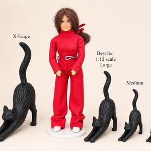May include: A doll wearing a red long-sleeved jumpsuit and white shoes stands next to four black cat figurines in varying sizes labeled X-Large, Best for 1:12 scale Large, Medium, and Small. Each cat is in a stretching pose with an arched tail.