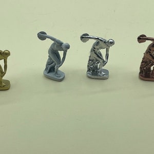 May include: Four miniature sculptures of the Discus Thrower, each in a different metallic finish: gold, silver, white, and bronze.