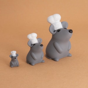 May include: Three gray mice figurines wearing white chef hats. The mice are different sizes, with the largest mouse standing in the back and the smallest mouse in the front.