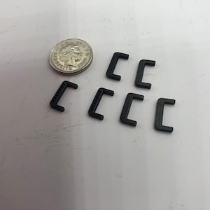 May include: Seven black plastic C-shaped brackets, approximately the size of a UK 20 pence coin.