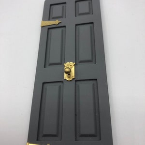 May include: A grey wooden door with six panels and gold-coloured hinges and a door knob.