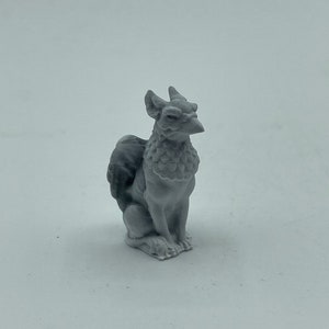 May include: A grey griffin figurine, a mythical creature with a lion's body and an eagle's head and wings. The griffin is seated, with its wings folded. The figurine is made of a solid material. The griffin is a popular fantasy figure.