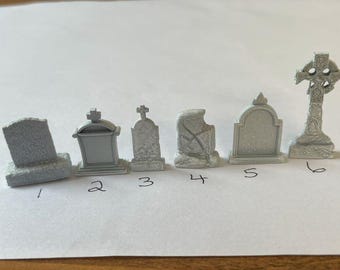 May include: Six miniature white painted tombstones, numbered 1 through 6, with a variety of styles and designs. The tombstones are made of a hard plastic material and are suitable for use in miniature games or model railroad layouts.