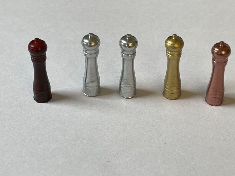 May include: Five salt and pepper shakers in different colors: red, silver, gold, and copper. The shakers are all the same size and shape, with a round top and a cylindrical body.